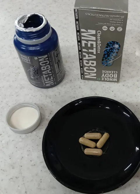 Metabon capsules on a black plate next to the bottle and box